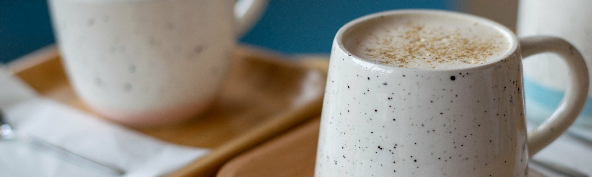 Zwei Keramiktassen mit Kaffee auf Holztabletts, eine mit Schaum und Gewürzen. Bilddatei: dummy.jpg.