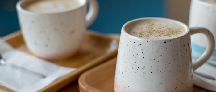 Zwei Keramiktassen mit Kaffee auf Holztabletts, eine mit Schaum und Gewürzen. Bilddatei: dummy.jpg.